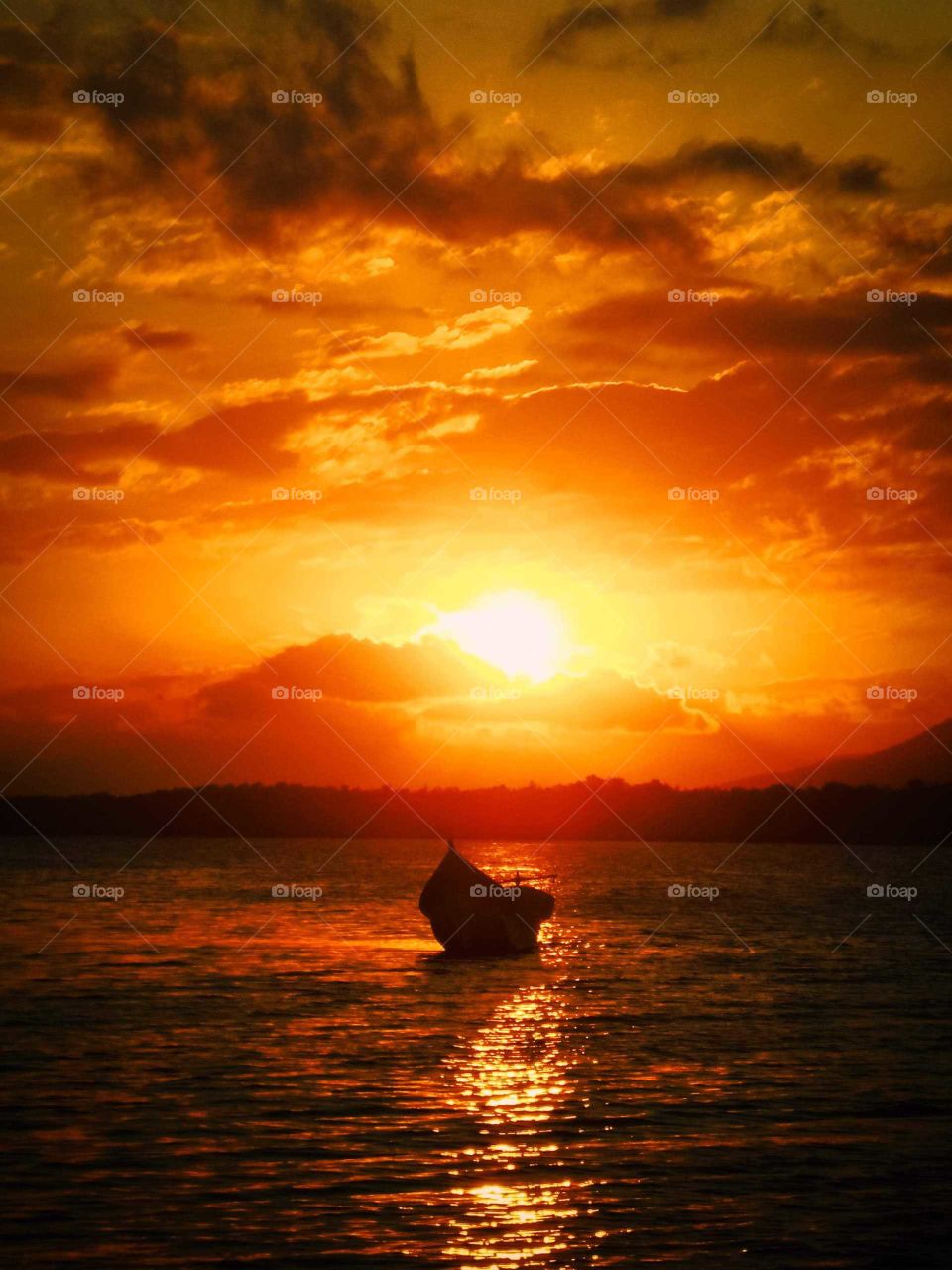 fisherman's boat at sunset, beautiful scene with orange golden hour sky, reflecting ocean, at Ilha do Cardoso, Brazil.
