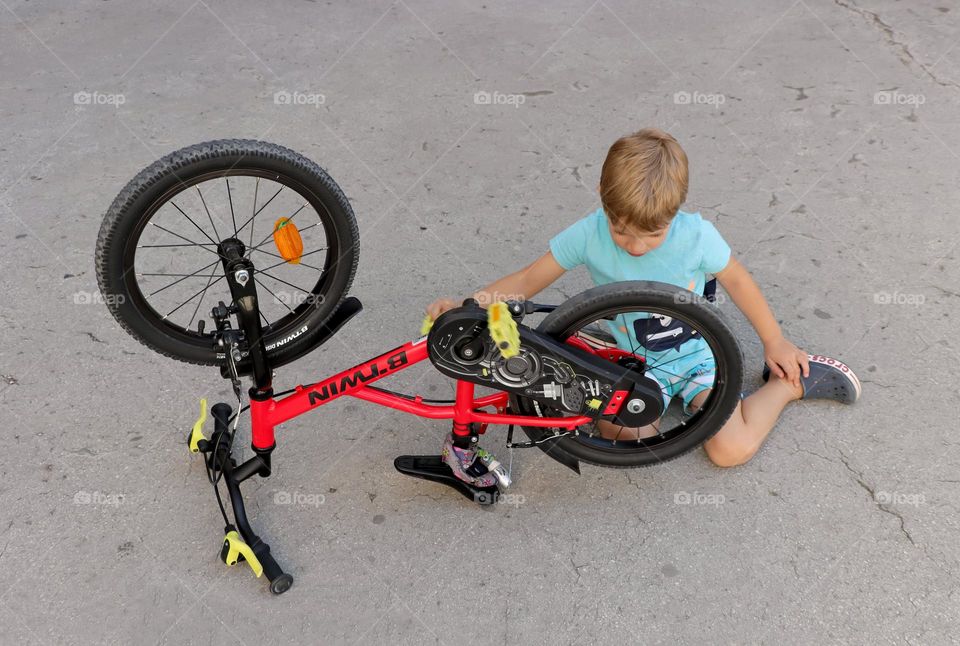 A boy's checking the correctness of the pedal of his bicycle