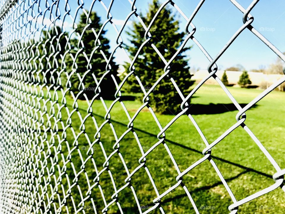 Closeup photo of chain link fence with beautiful green grassy field in background!