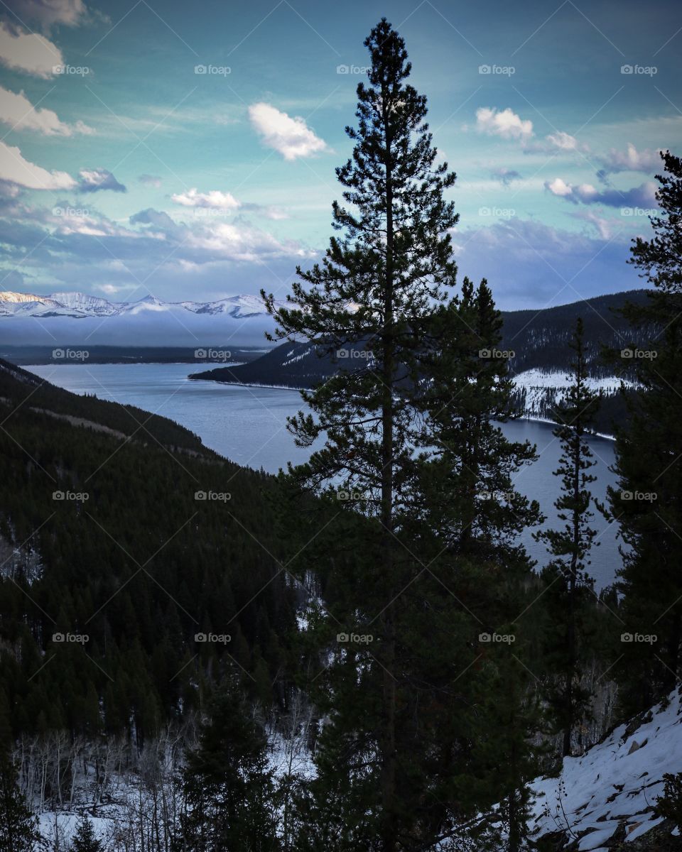 Hidden lake in the mountains. A cold and windy day with blowing clouds. Surrounded in the evergreen trees.