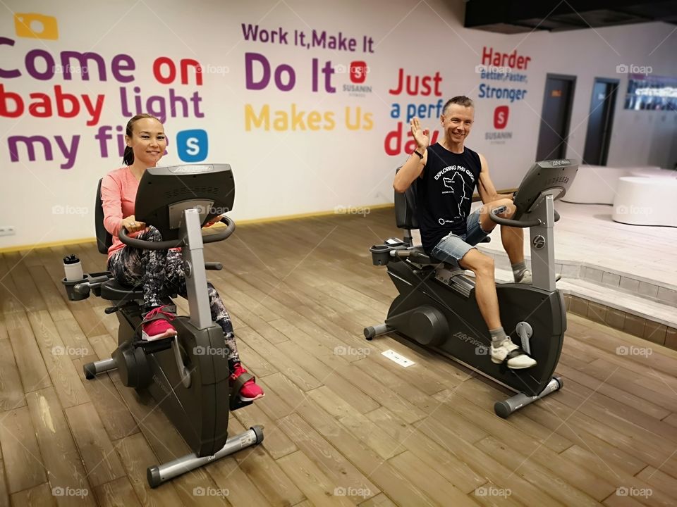 A smiling couple training in gym. Happy man and woman exercising in gym. Fitness Jogging Training Healthy lifestyle Concept.