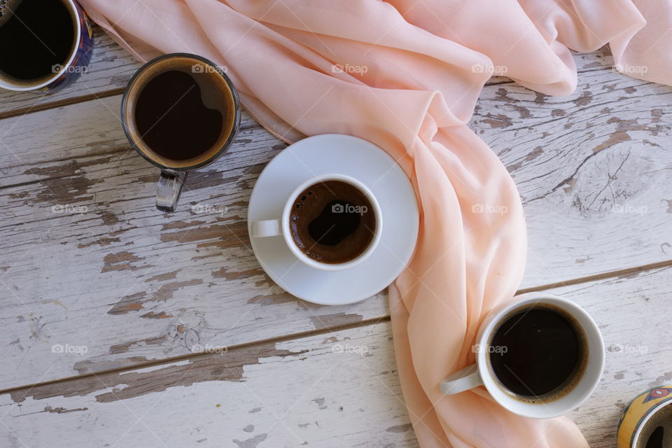 four mugs of coffee and beige cloth