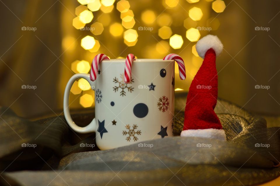 a cup of tea in christmas version with hat of santa claus and candy canes