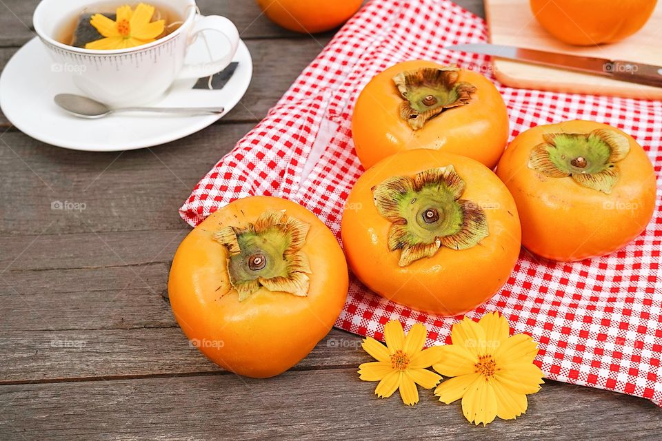 Persimmons. Fresh persimmons on the wooden table with red and white gingham pattern picnic mat.