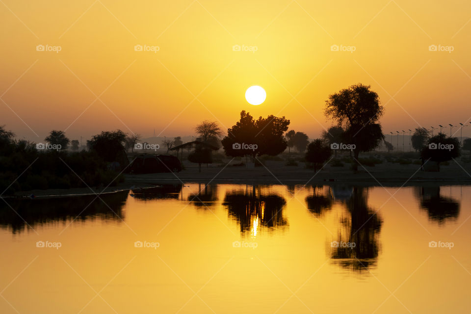 Sunrise at the lake with trees reflecting in it