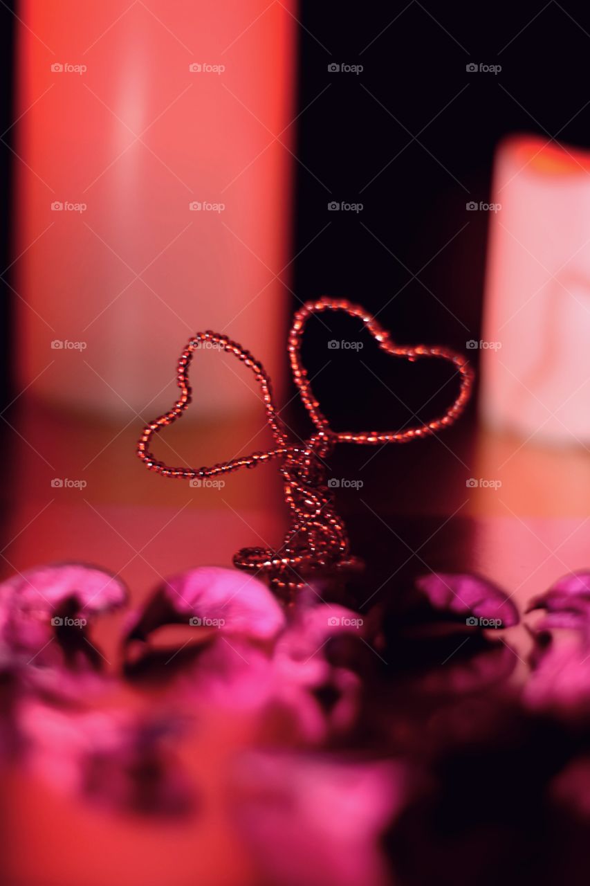Tree love of red beads. Two hearts entwined together. Background is highlighted by a led lamp