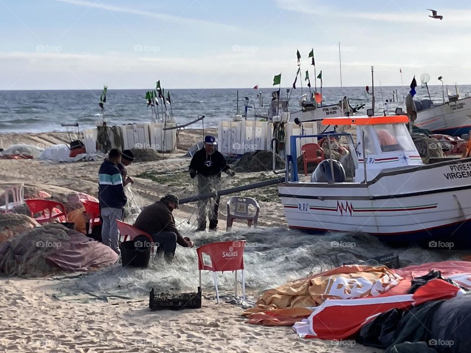 Fishermen near their boats cleaning nets