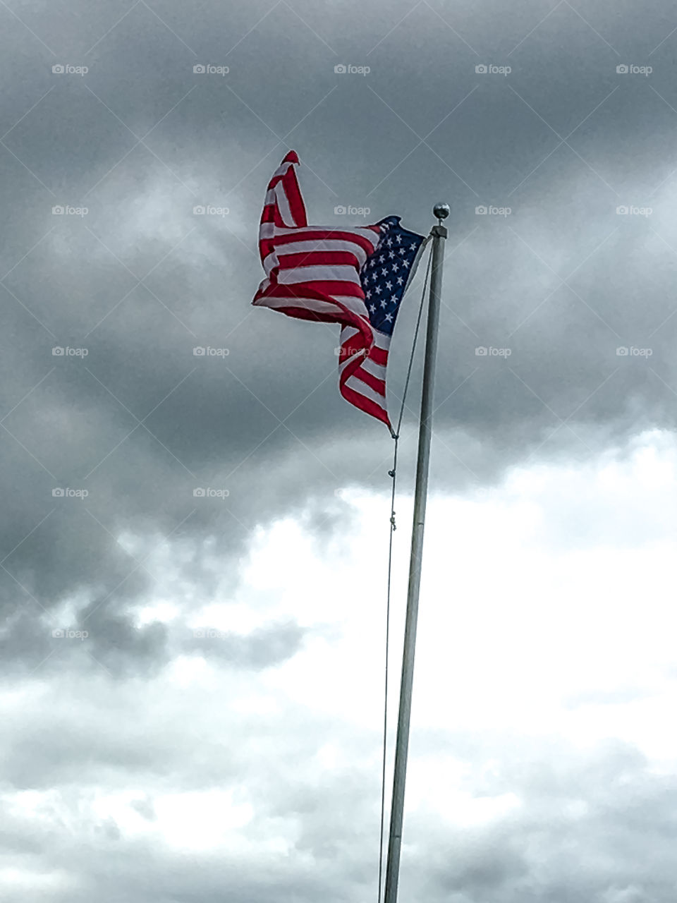 USA flag flying on flagpole during storm