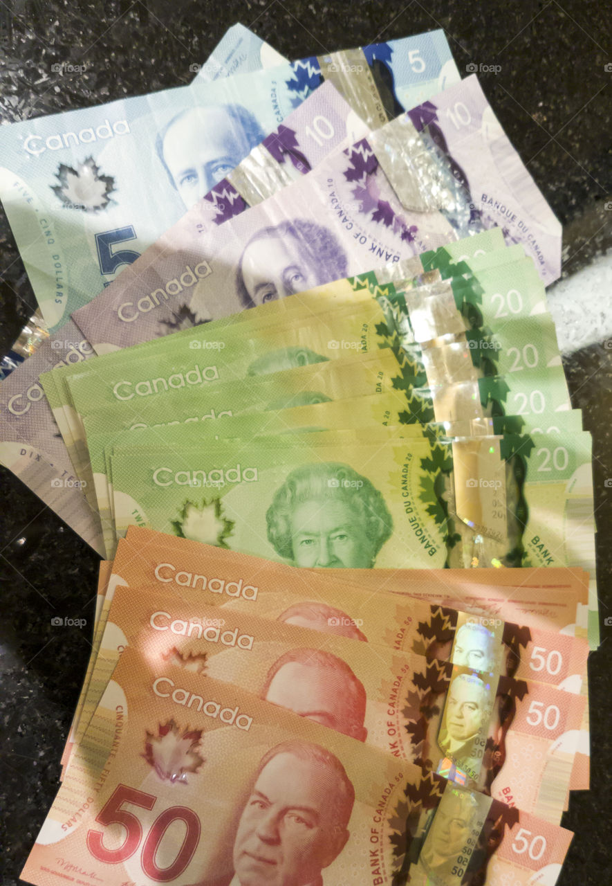 Canadian dollar bank notes currency.
A close up pile view of 5 10 20 and 50 Canadian dollars.
