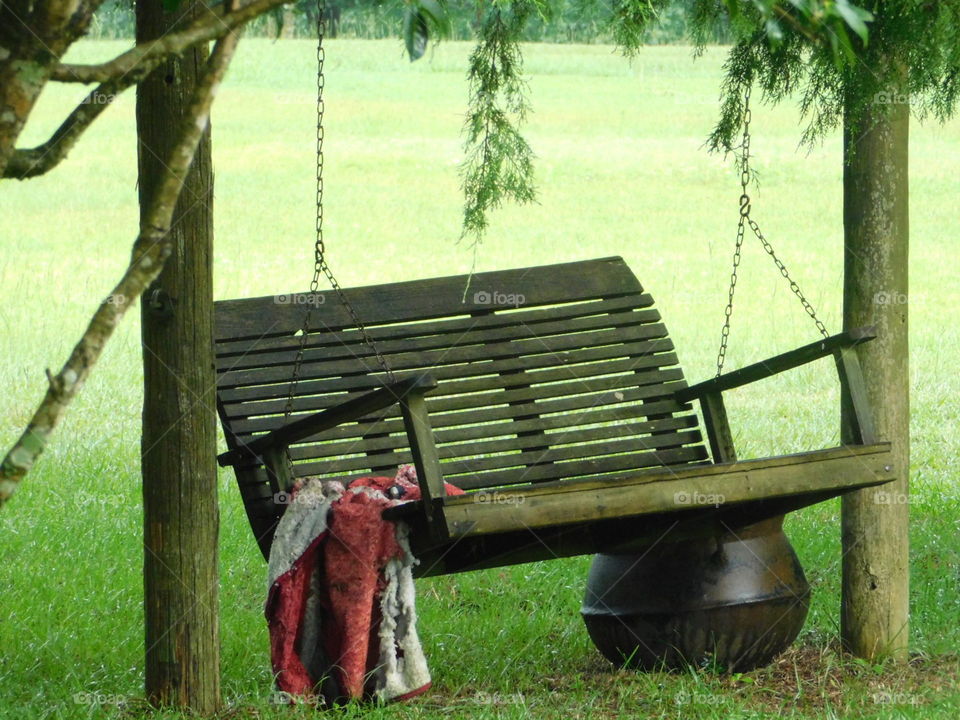 Rustic wooden classic swing set with red blanket in field