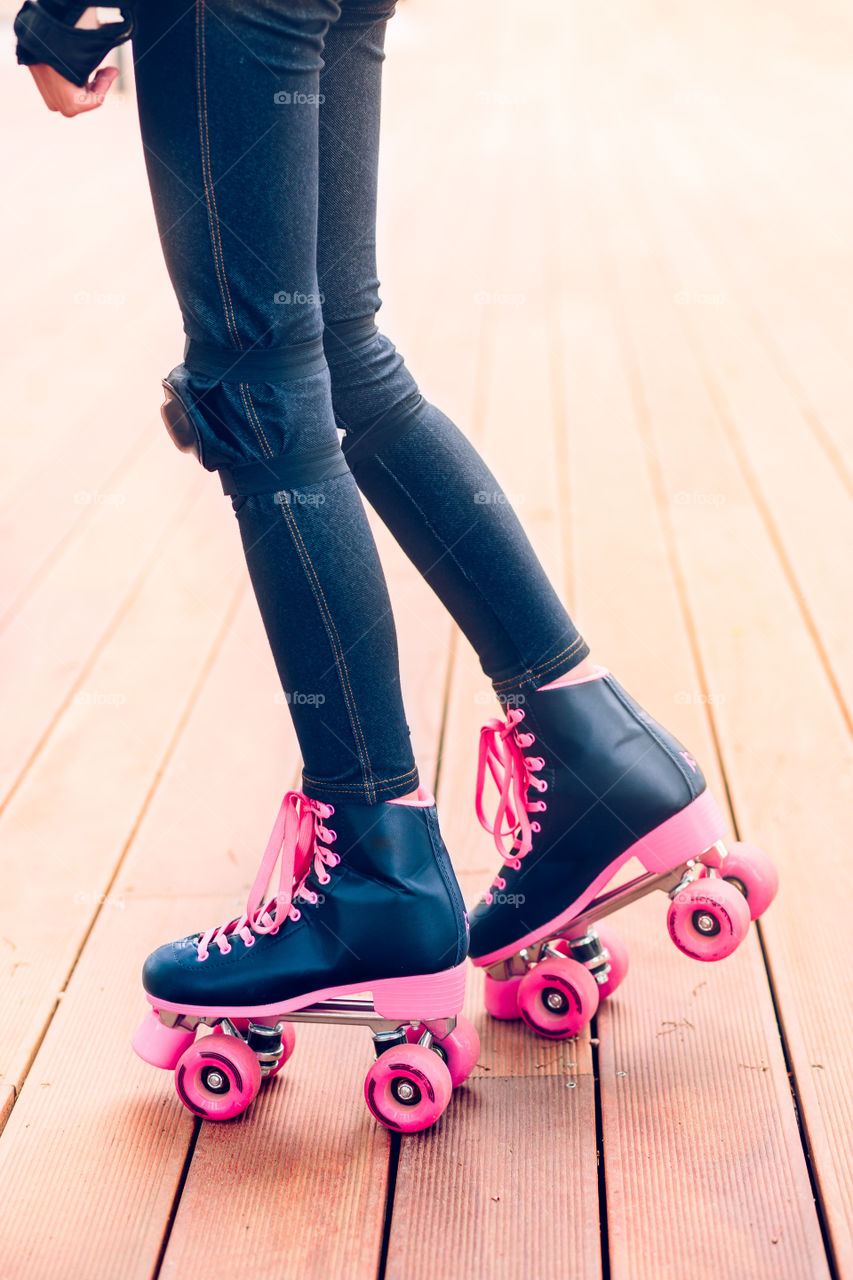 Close-up of female legs in roller blades on wood