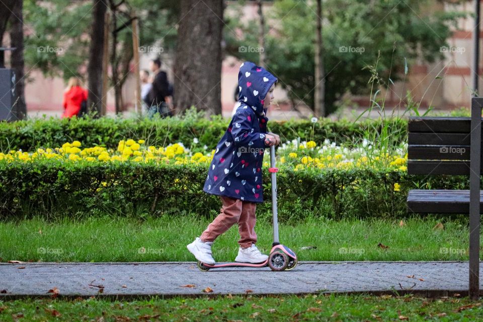 A girl on a scooter in the park