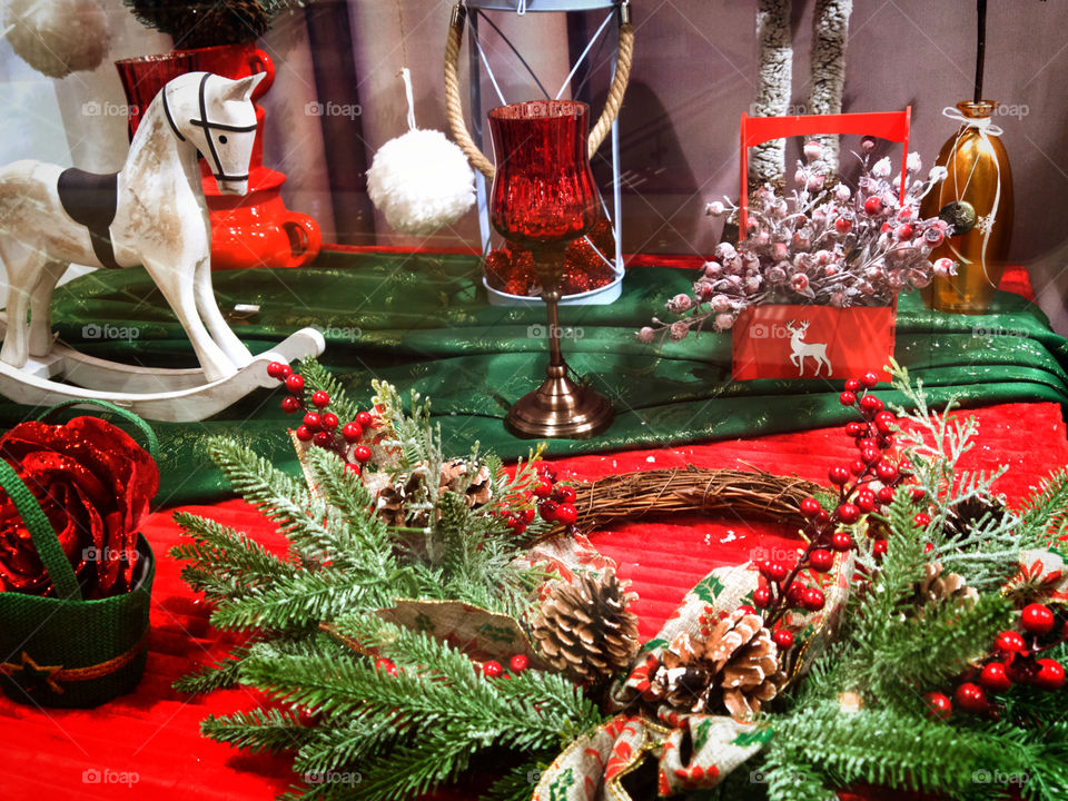 Winter composition: fir branches with cones, a wreath of tree branches with red berries, a lantern and a rocking in the form of a white horse.
