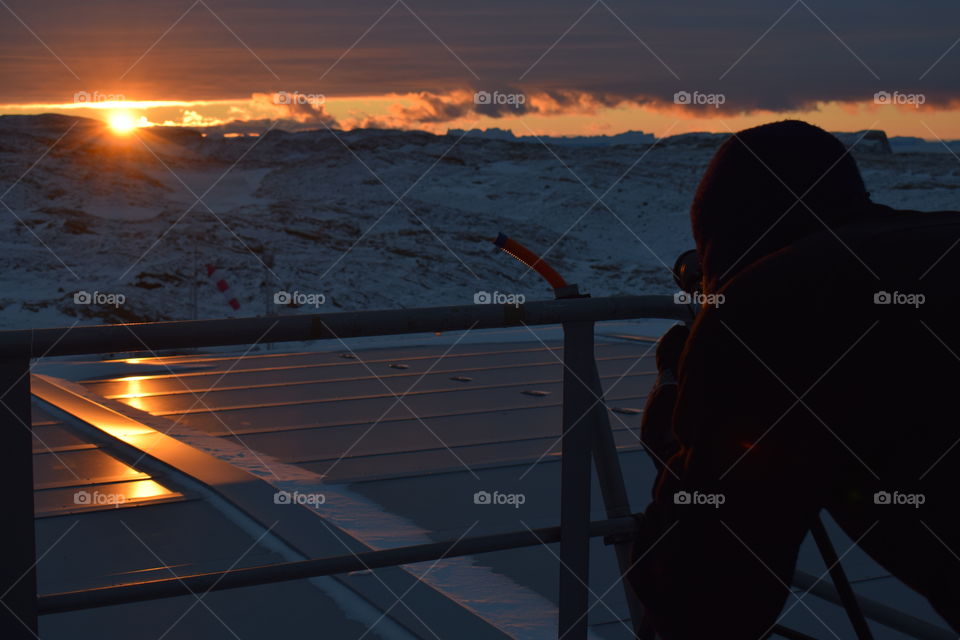 Picture of photographer , trying to take pictures of the sunset on a sunny day at south Pole. 