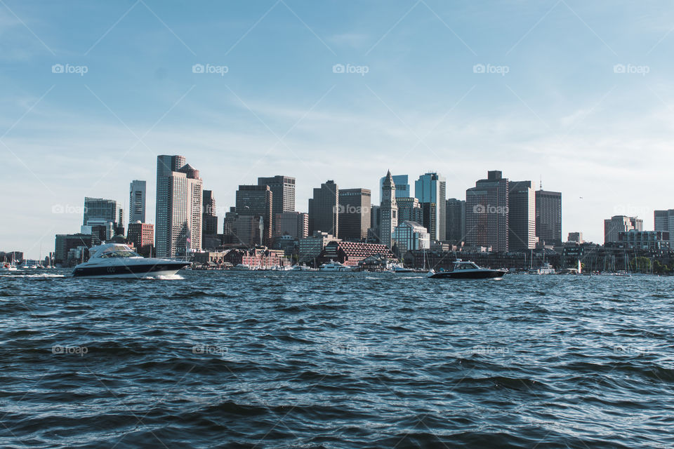 Boston Harbor with the skyline and boats going by the water