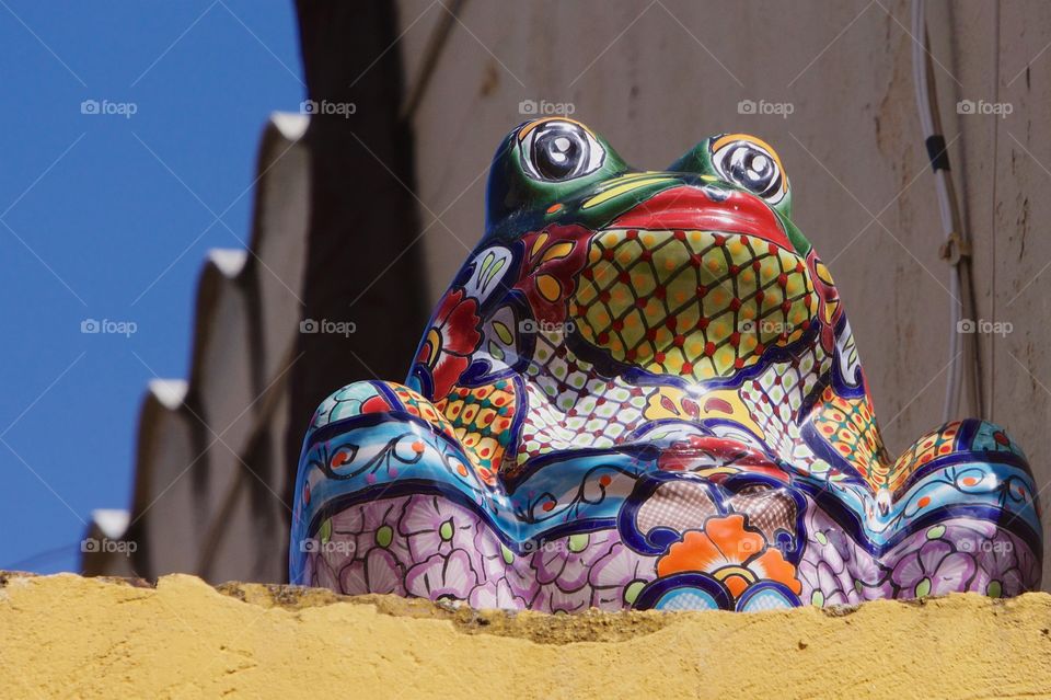A multicolored ceramic frog  on the roof of a house in San Miguel de Allende, Mexico overlooking the street.
