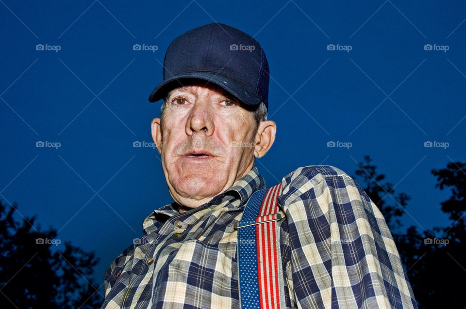 An elderly man with American flag suspenders