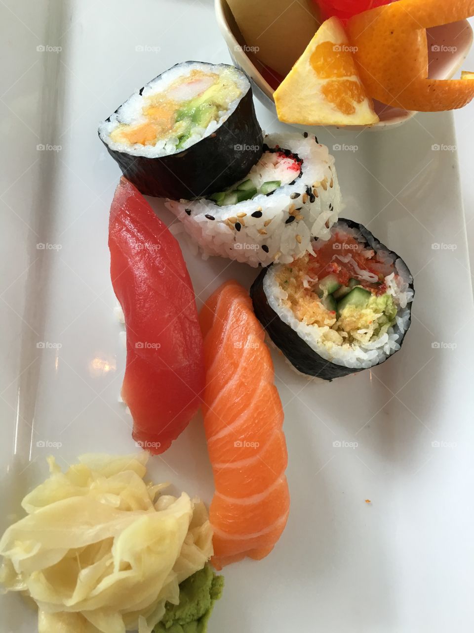 Sashimi and maki rolls on clean white plate closeup Japanese food 