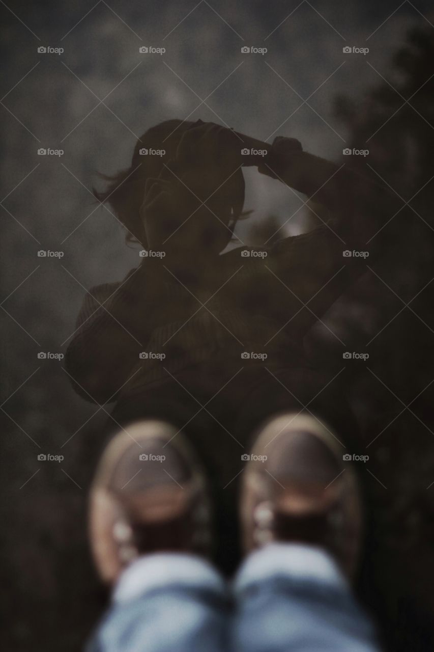 Self portrait of a girl in brown sneakers in a reflection of a puddle