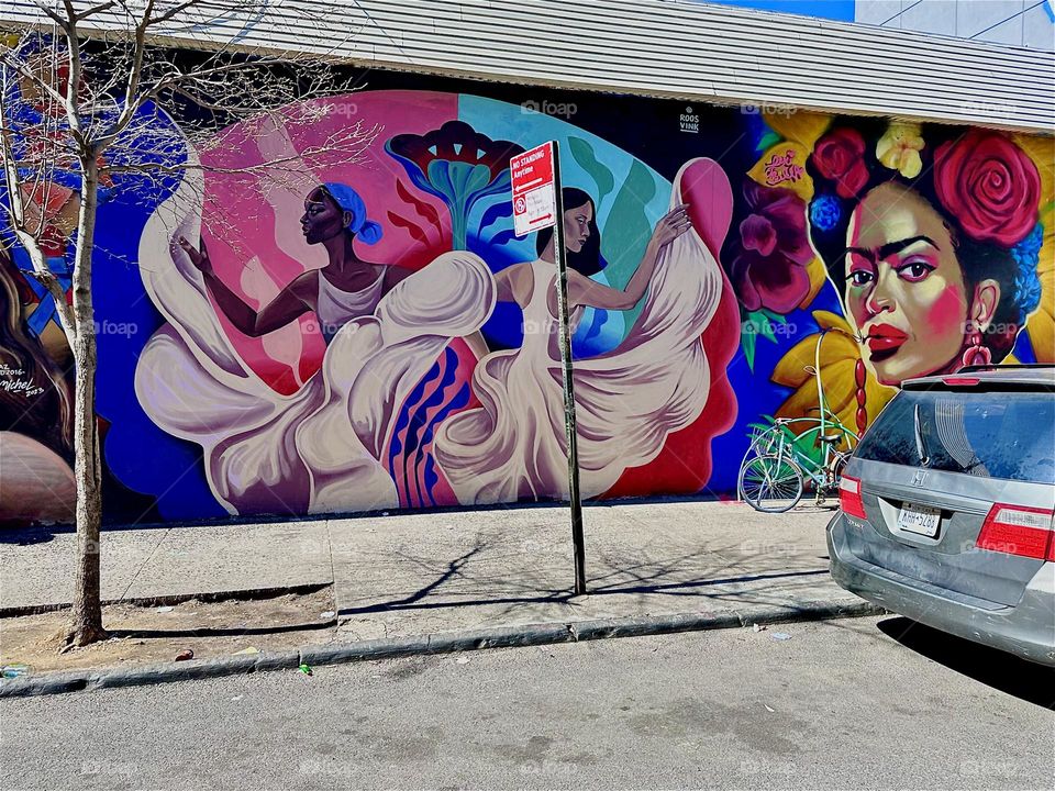 This is a section of a beautiful art mural on „Jefferson Street“ off „Broadway“ in „Bushwick“, Brooklyn showing two dark skinned Latina dancers in long flowing white dresses. 2024. Hypnotic Productions