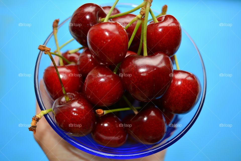 Human hand holding bowl of cherry