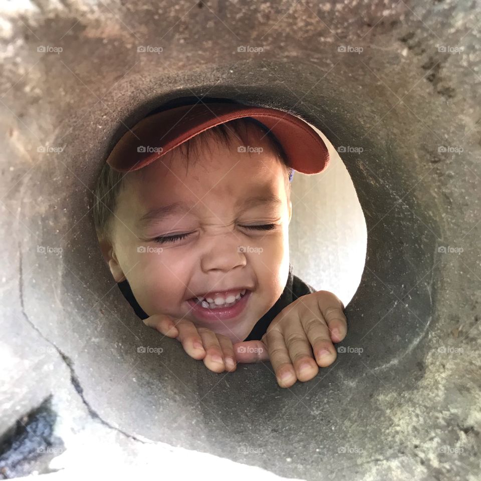 Young boy grinning through a hole at the Lincoln Park Zoo in Chicago