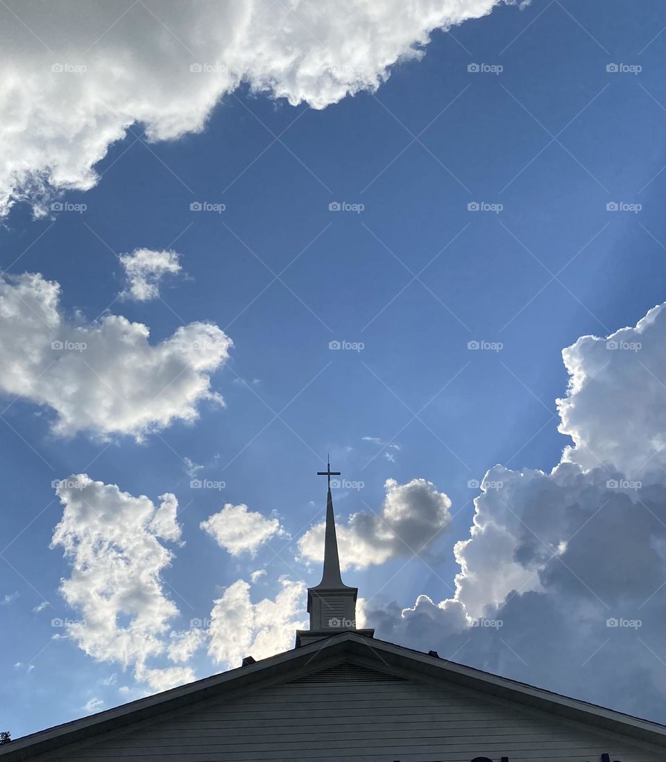 Church steeple silhouette against a blue sky, from the ground up