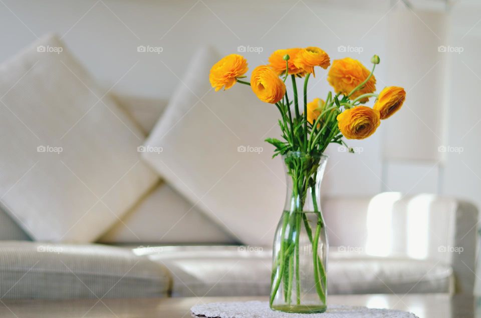 Top view of yellow flowers in a vase at table at cozy home.  Bouquet of ranunculuses close up. Holiday concept. Gift ideas