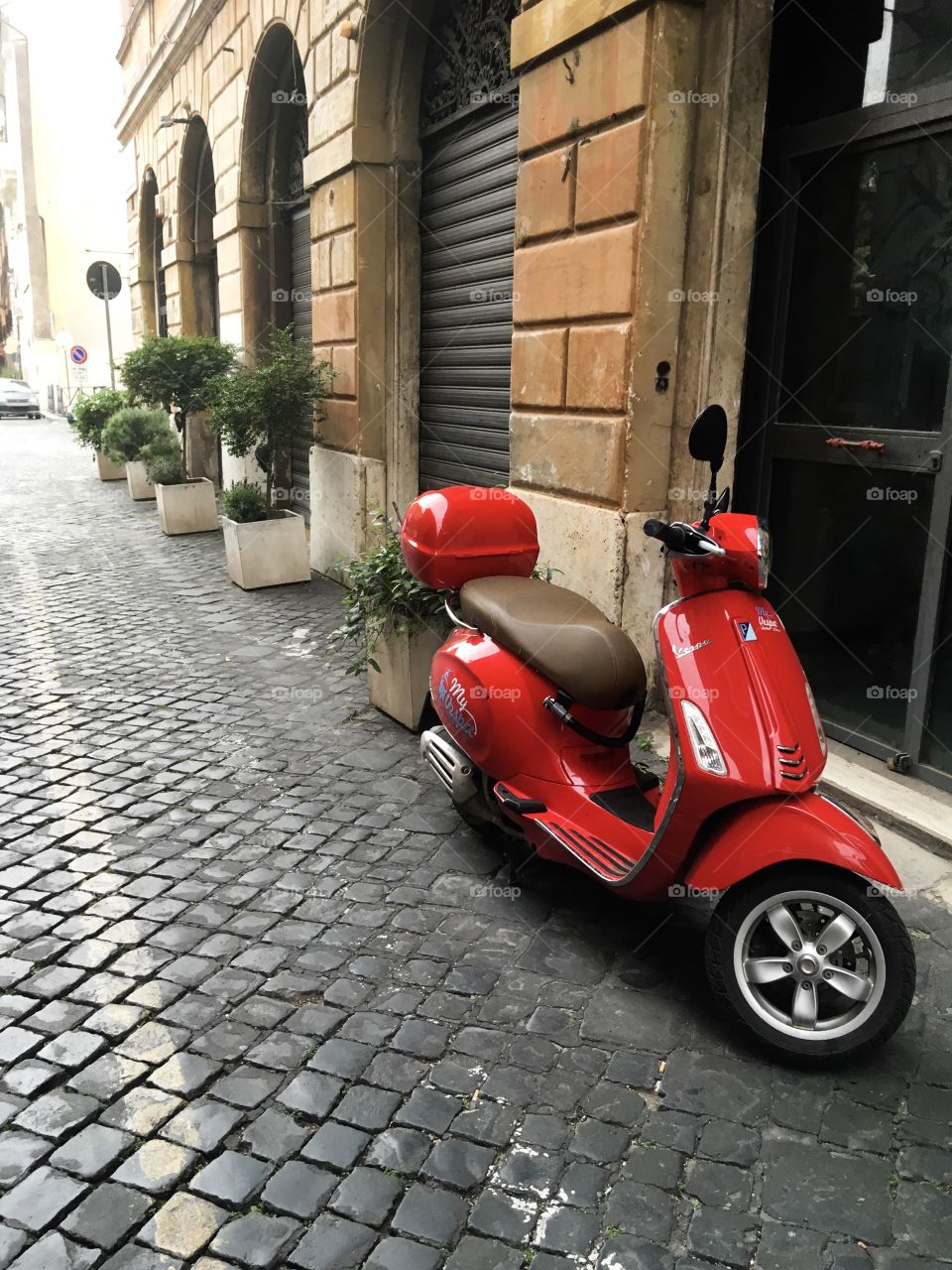 The red scooter at the Rome street. Rainy day. 