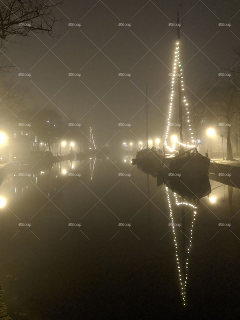 Old sailing boats in misty harbour in the night