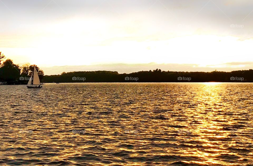 Sail boat sailing on Hamlin Lake at sunset—taken in Ludington, Michigan 