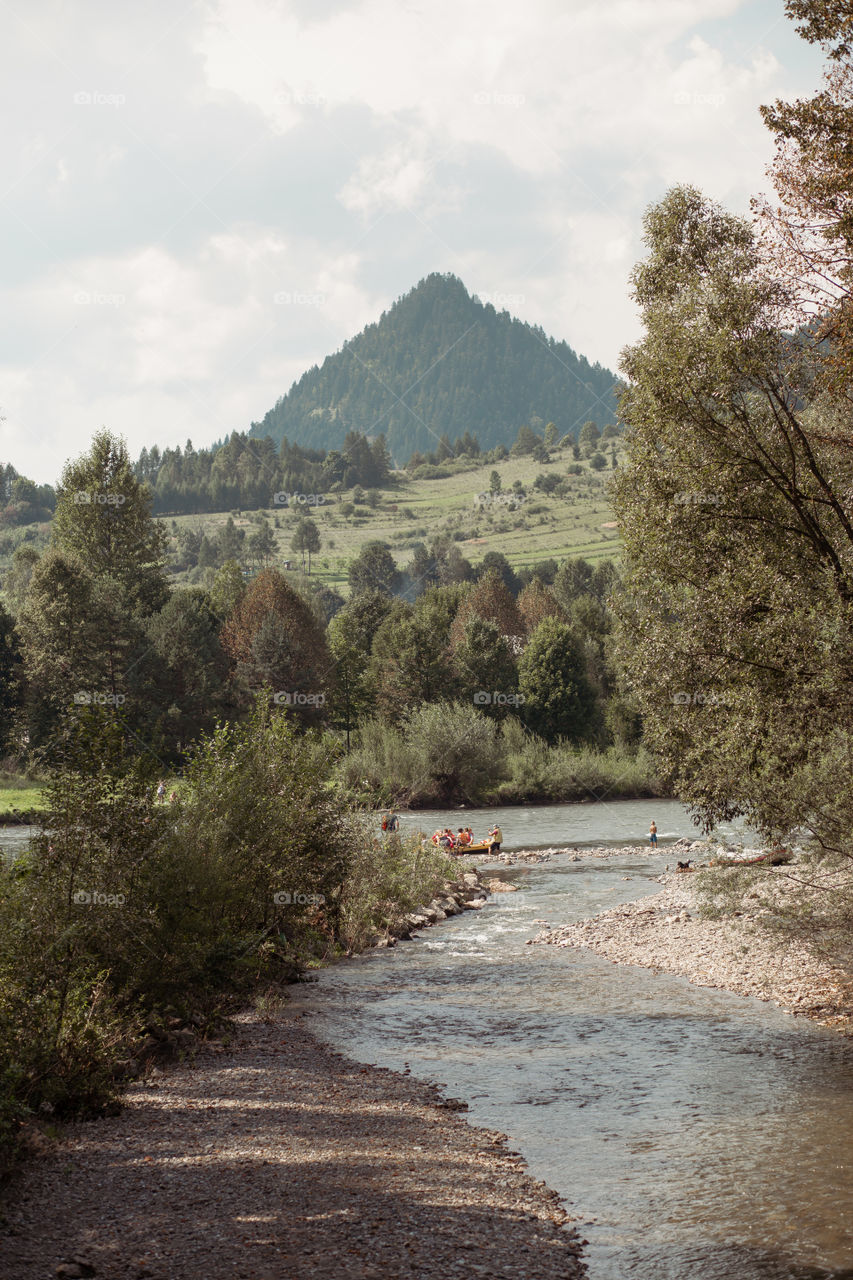 Mountain river valley landscape. Beautiful natural scenery. Dunajec river at the foot of peak in the Pieniny Mountains. People spending time over the river