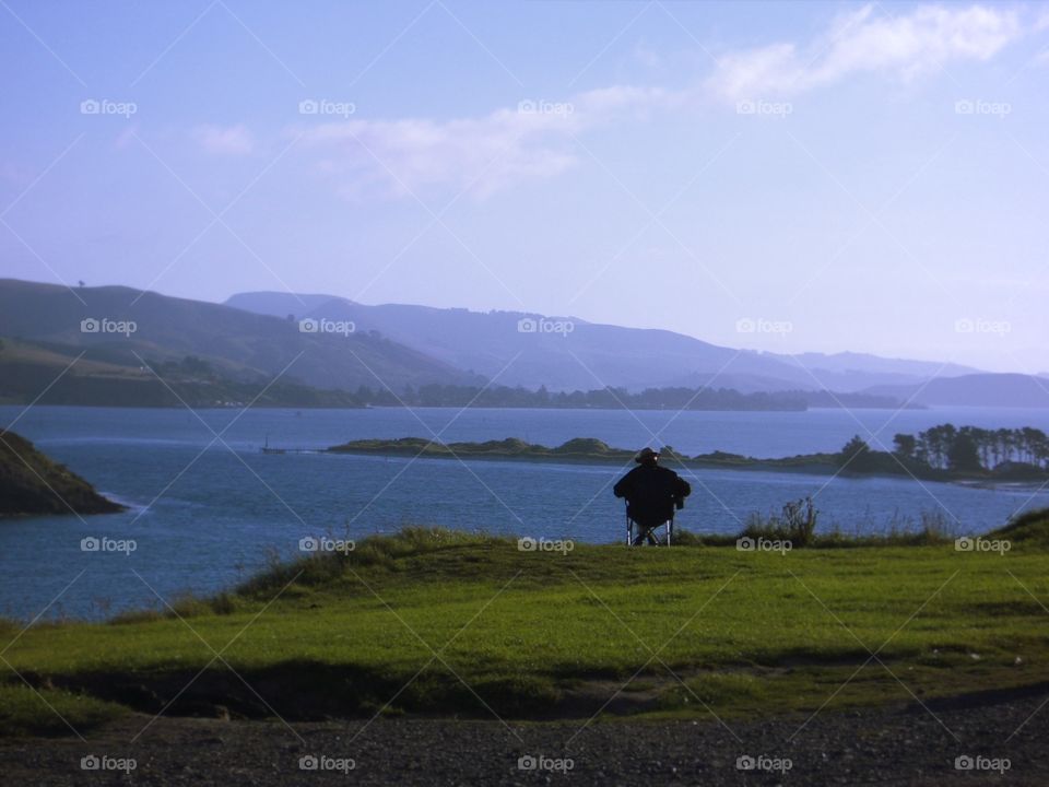 Old man painting the mountain range at Harington Point, New Zealand.