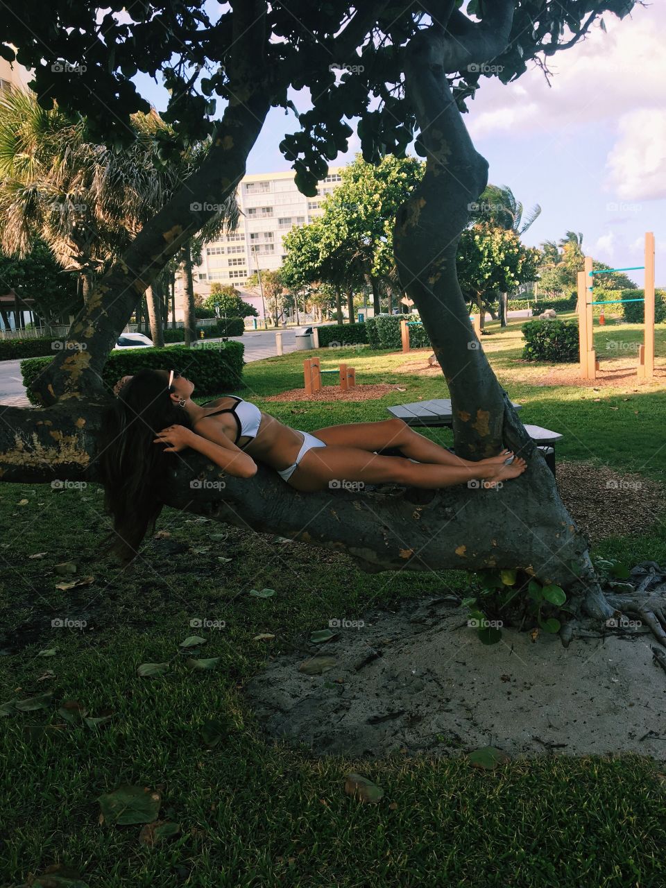 Woman in bikini lying on tree trunk