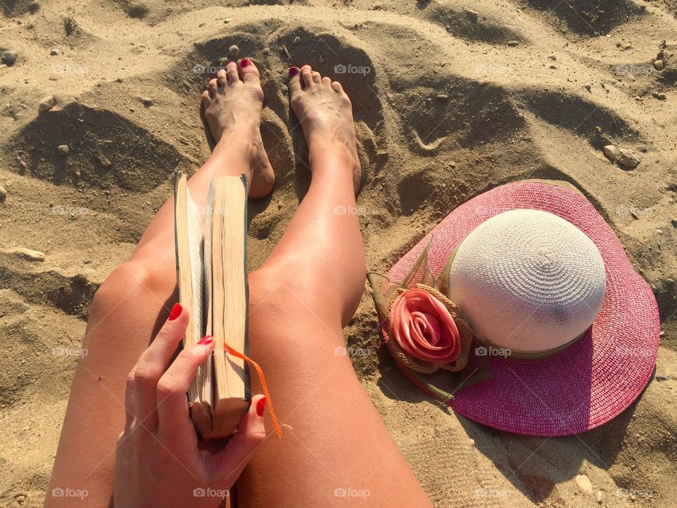 Woman reading on the beach with summer hat near