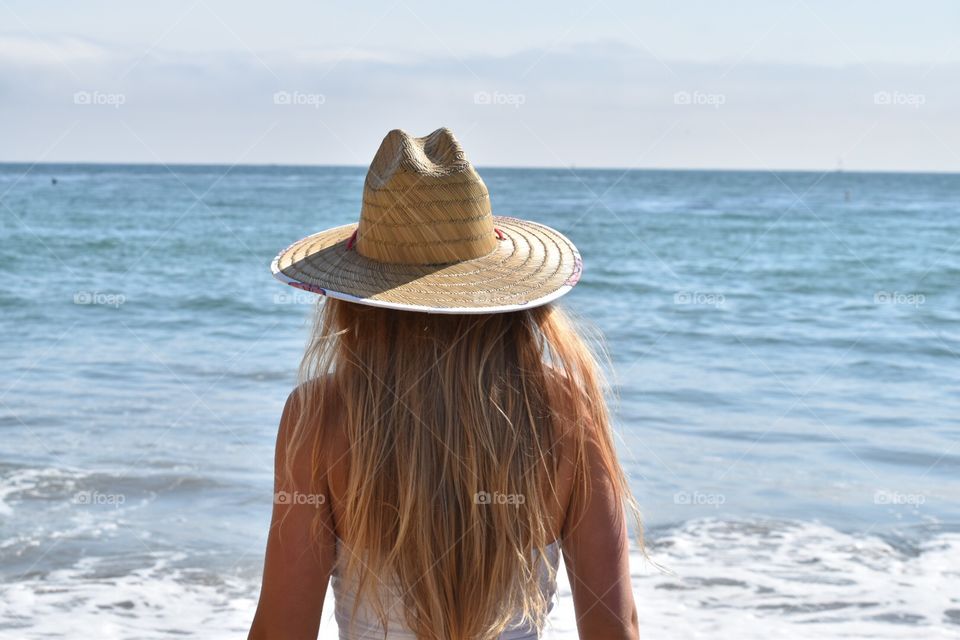 back of girl at beach with blonde hair and hat