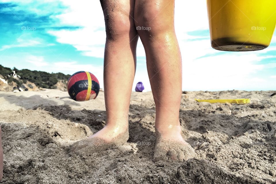 Boy playing with a bucket on the beach 