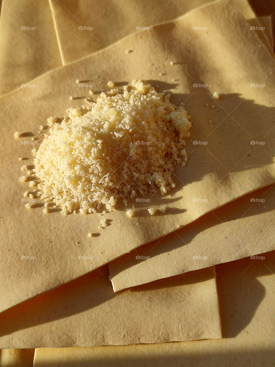 The grated Parmesan cheese lies on layers of Lasagne.