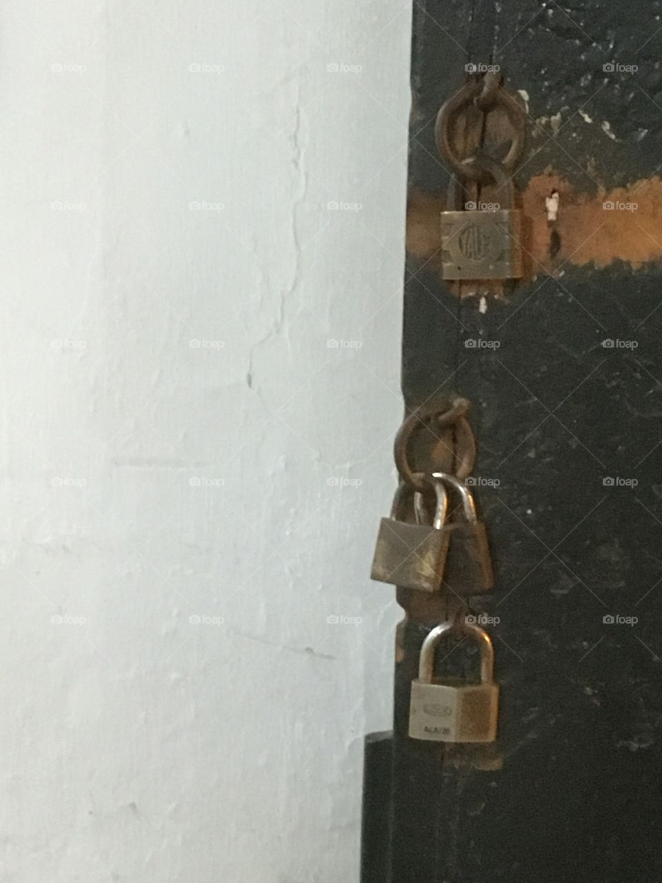 Locks on a door next to a white wall. 