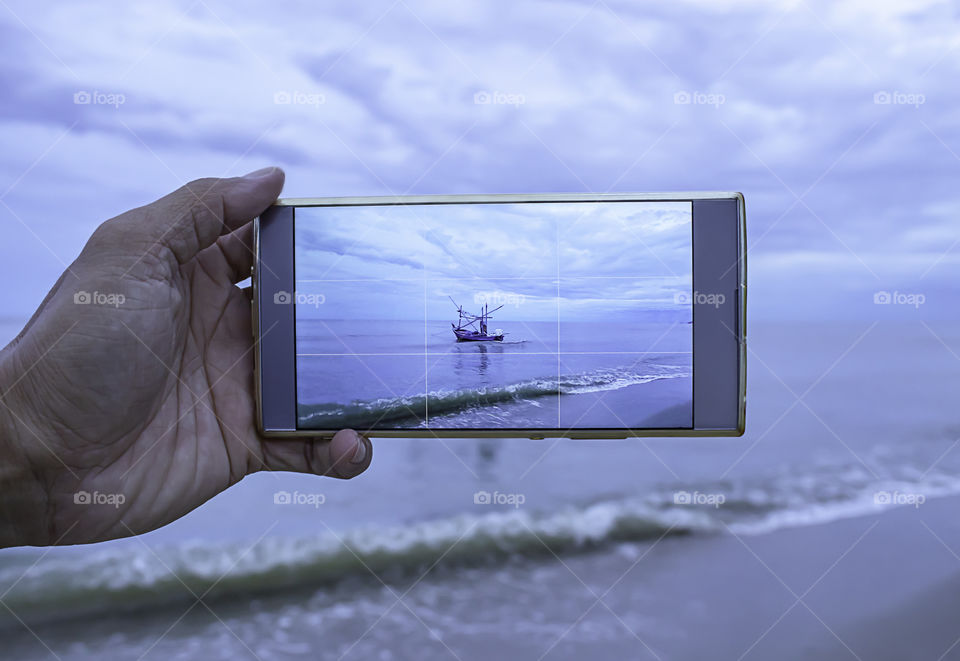 Photos of the fishing boat and the sky with clouds covered on the phone.