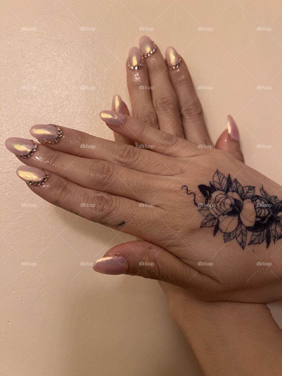 Pink chrome nails with rhinestones and a hand tattoo