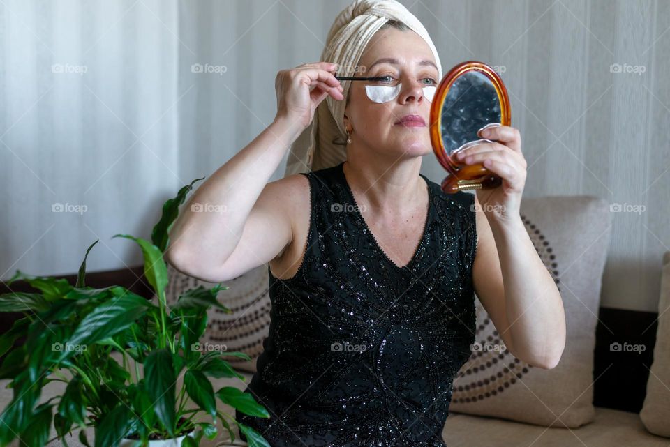 Home beauty salon woman makes mask patches for eyes and paints eyes with mascara