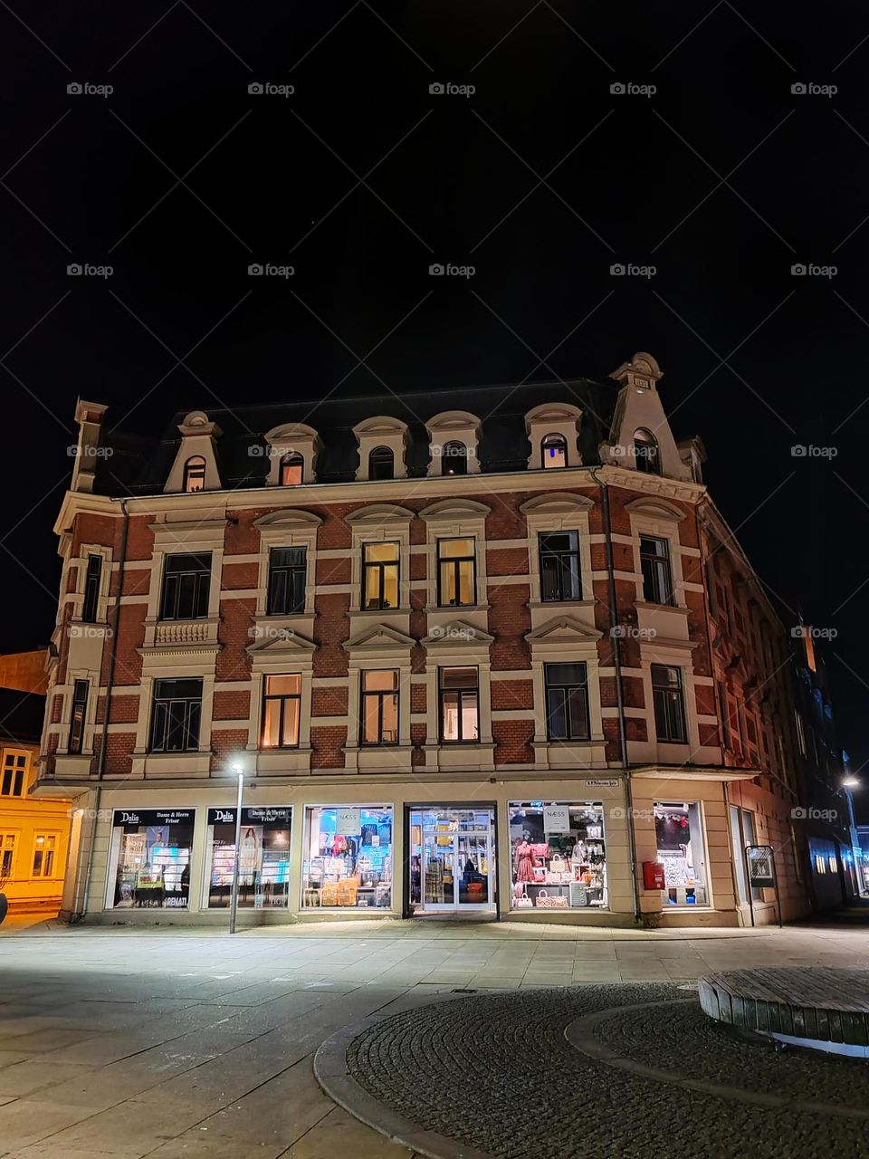 The architecture is traditional, with a warm, historic charm. The building features a combination of red brick and light stone details, including window sills and decorative moldings around the windows.
