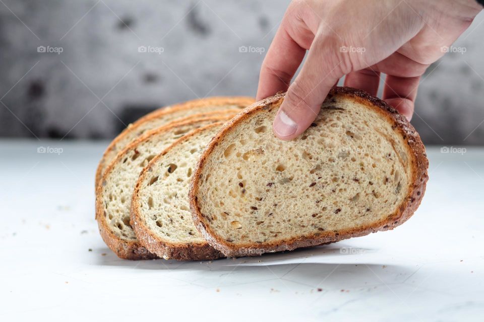 Boy's hand is reaching for a piece of fresh bread