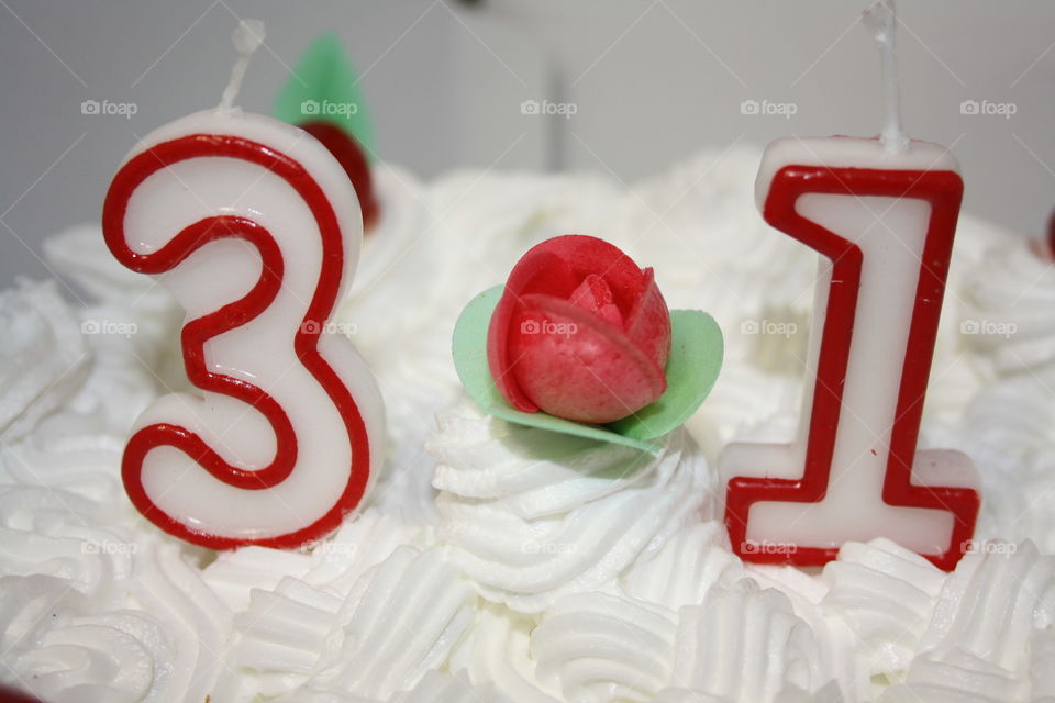 It's a birthday cake. The age of the model is thirty-one years old. I have focused with the camera so that the candles and the cream can be seen. In the middle of the candles there is a sugar rose.