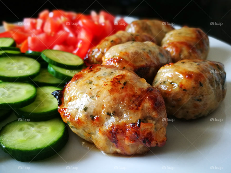 Grilled Sausages with Fresh Vegetables (Cucumber and Tomato) on a White Plate. Traditional Cypriot food: Sheftalia : Cypriot Lamb and Pork Sausages.