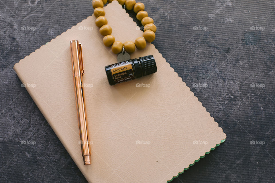 Motivate doterra essential oil bottle on cream notebook with rose gold pen and mustard bead bracelet 