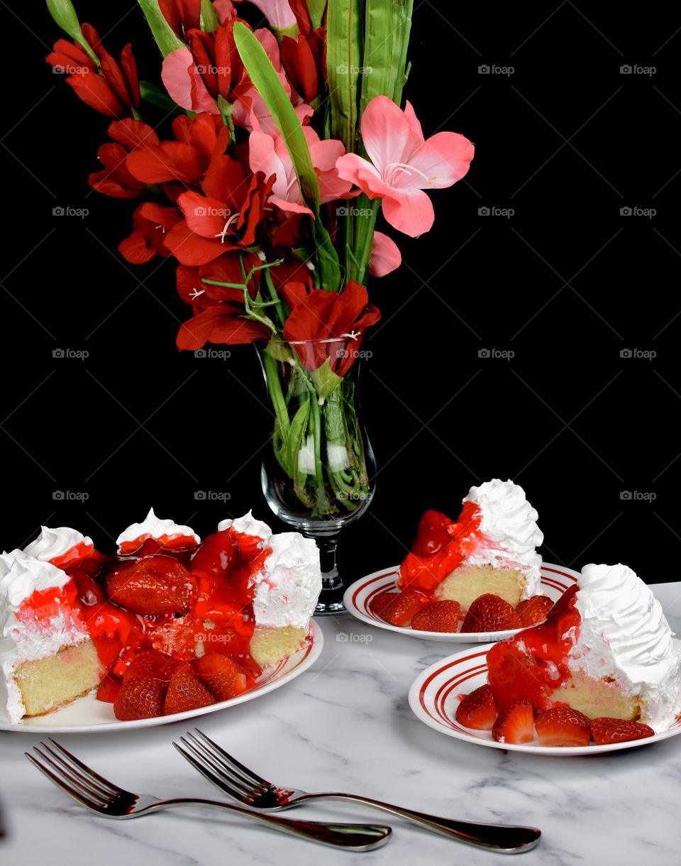 Delicious strawberry cake with a vase of red flowers