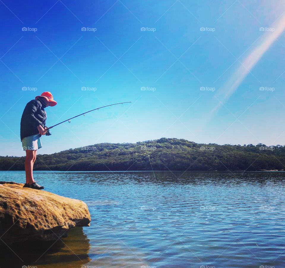 Fishing off a rock on the lake 