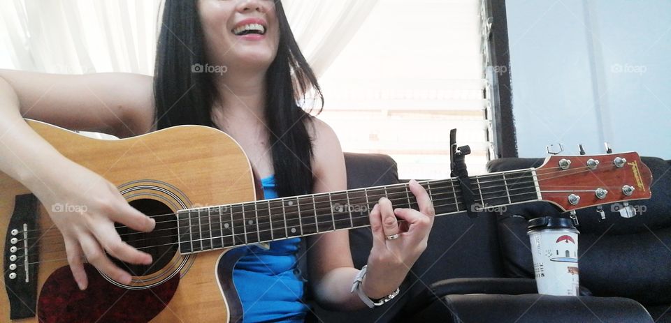 A woman playing the guitar happily.